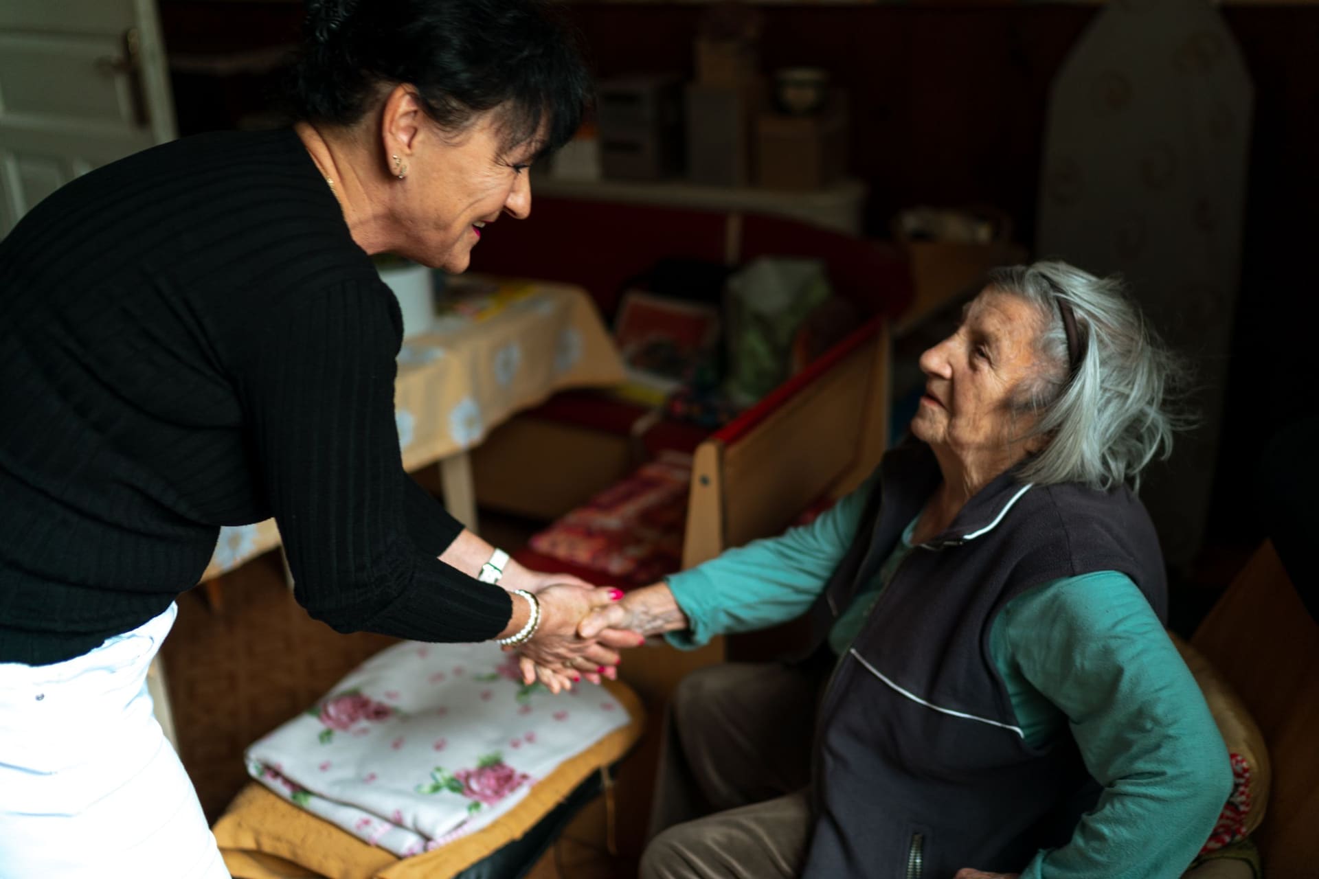 Osobní asistentka zdraví seniorku v jejím domácím prostředí